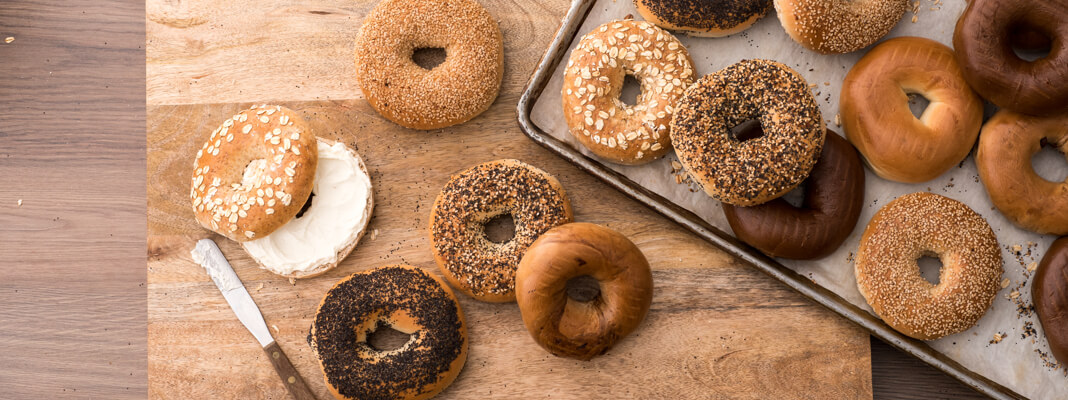 Assortment of bagels on a cutting board with cream cheese