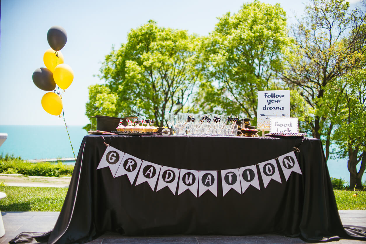 A food table with a black table cloth set up outside for a 2021 graduation party