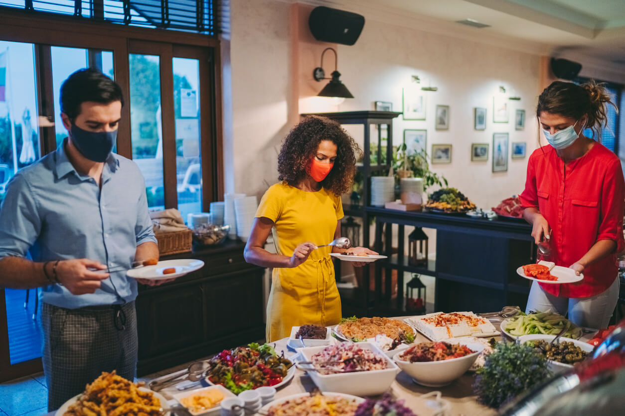 ocially distant event planning a party for masked guests choosing food from a buffet spread