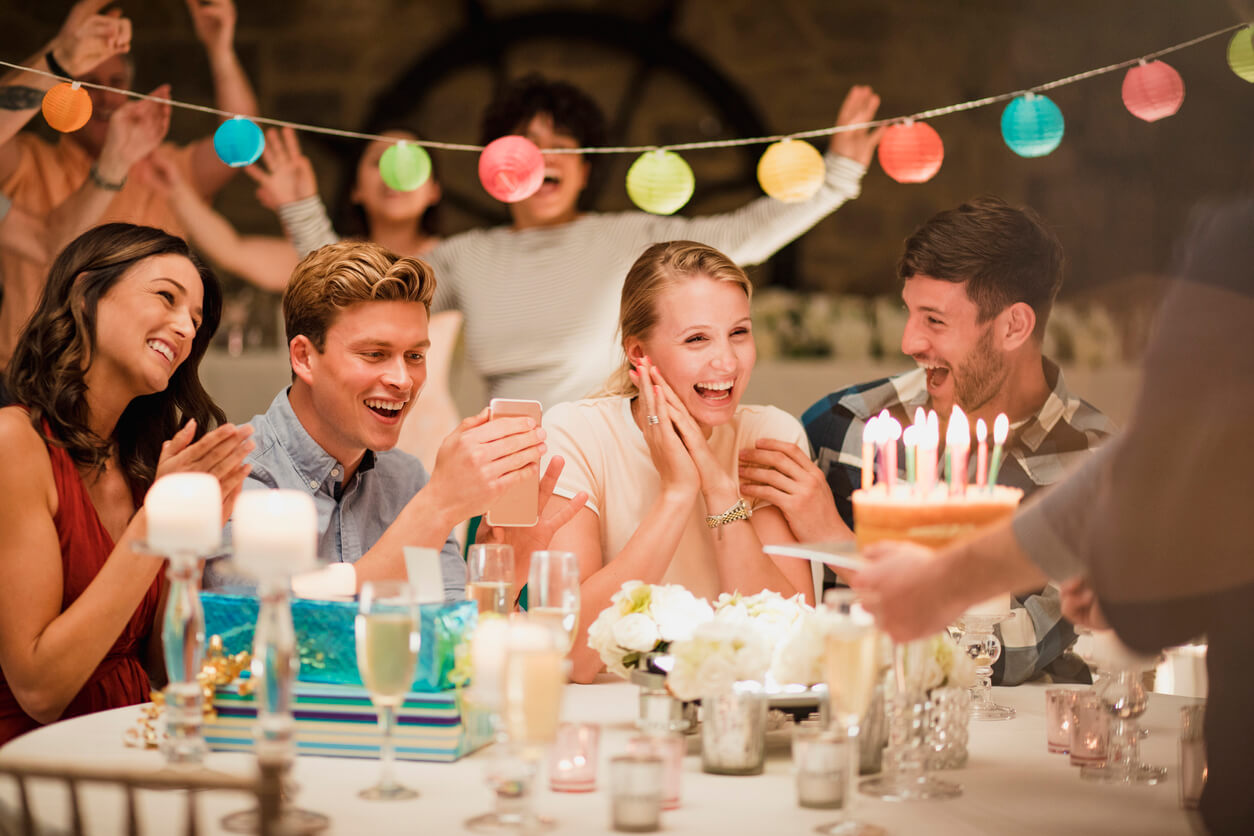 Happy friends celebrating a milestone birthday party amid a colorful table and decorations.