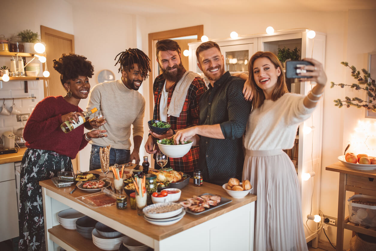 Friends enjoy food from and take a group picture at a housewarming party