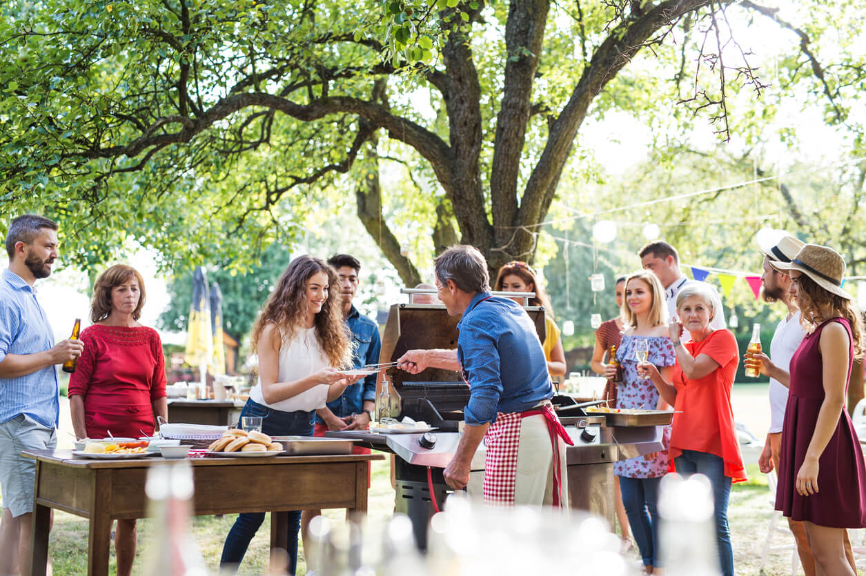 Employees gather around the grill at an office barbecue outside
