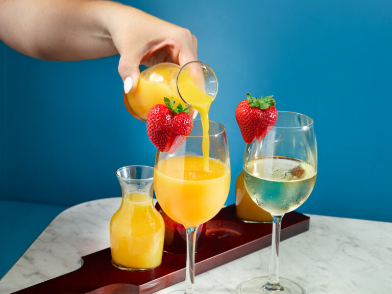 pouring OJ into a mimosa